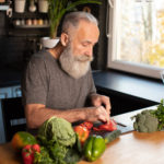 Bearded senior Man preparing healthy and tasty salad in kitchen.